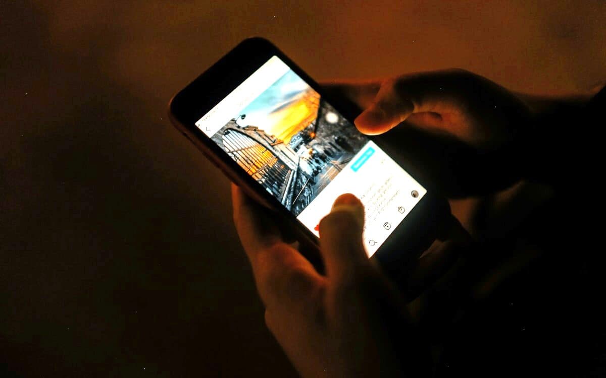 Two hands working a phone in the dark, a short vertical post open on the screen