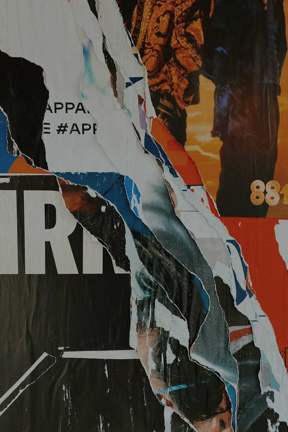 A wall of pasted paper torn back on the diagonal through several layers of print